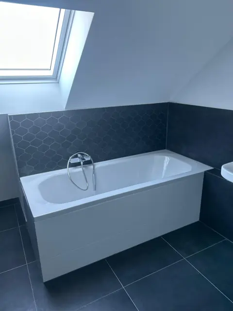 Einbaubadewanne vor einer Wand mit anthrazitfarbenem Sechseck-Mosaik