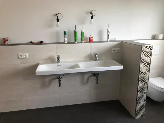 Doppelwaschtisch mit Fliesenablage und Mosaikstreifen an der Vorwand