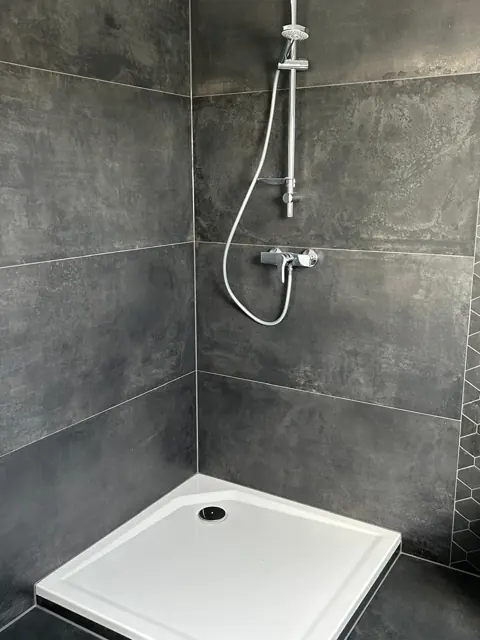 Dusche mit anthrazitfarbenen Großformatfliesen und Duschwanne