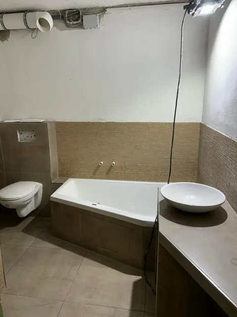 Eckbadewanne mit gefliester Verkleidung und Mosaikband